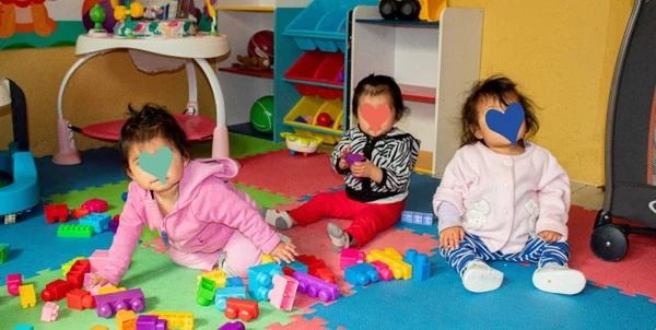 Tres bebés jugando con bloques de colores en el área de aprendizaje