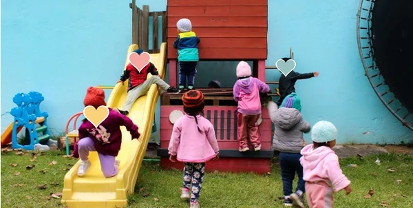 Niñas y niños jugando en el tobogán y la casita del jardín