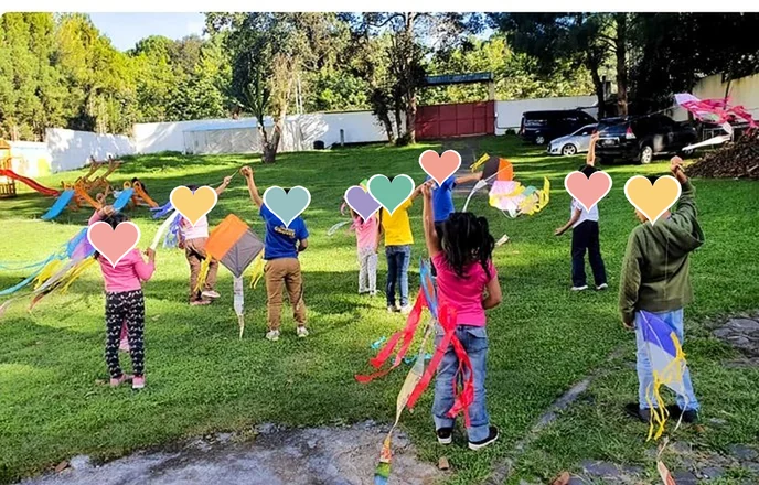 Niñas y niños volando barriletes en el jardín del Hogar