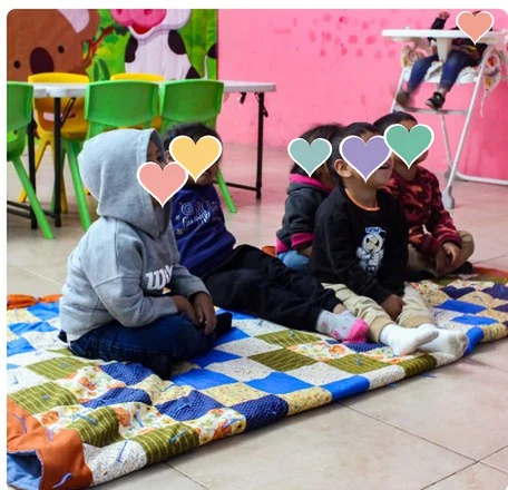 Niñas y niños sentados sobre una manta de colores